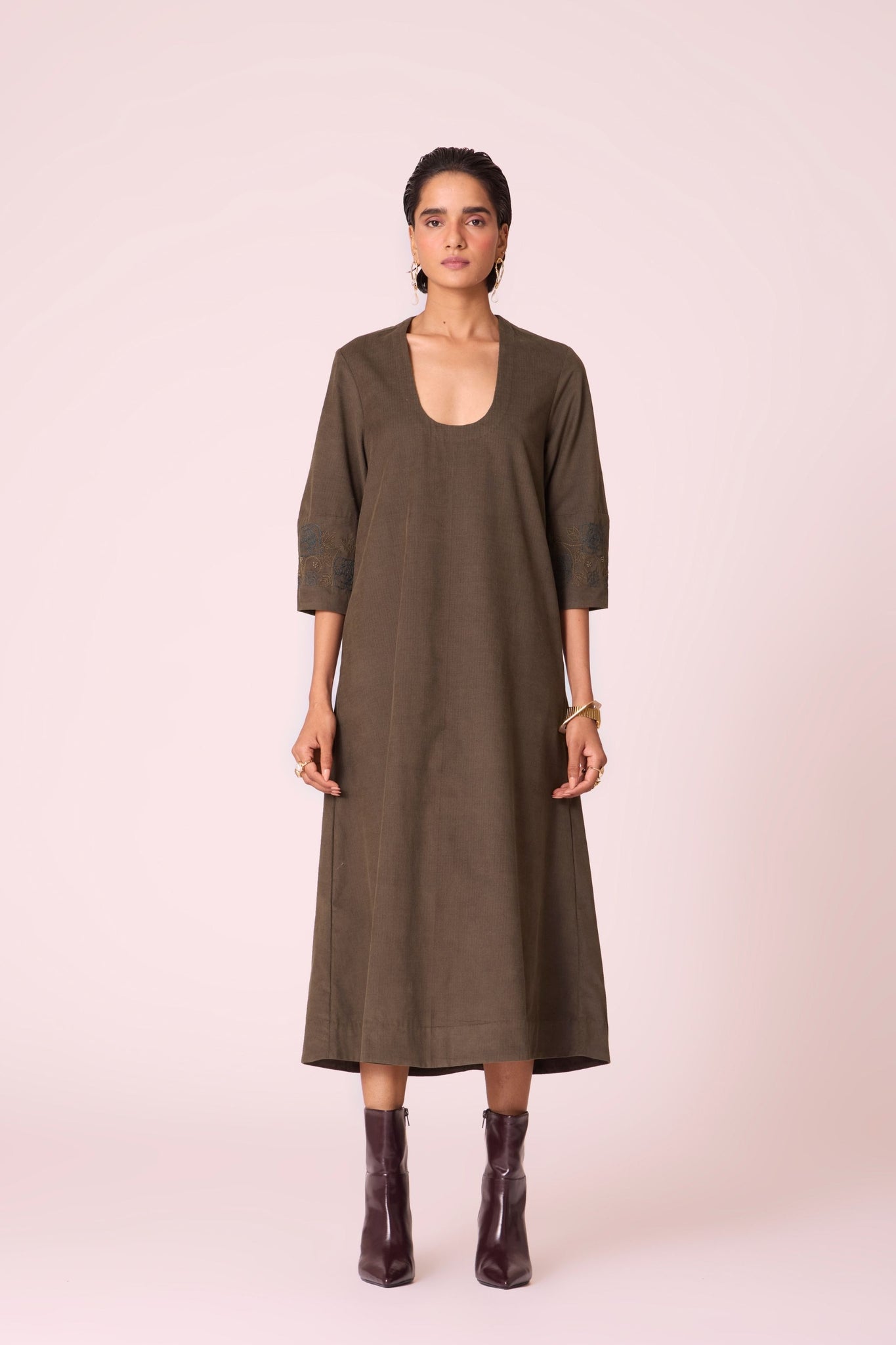 Olive needlecord A-line dress with drop shoulder, hand-embroidered cuff, deep scoop neckline, and in-seam pockets.