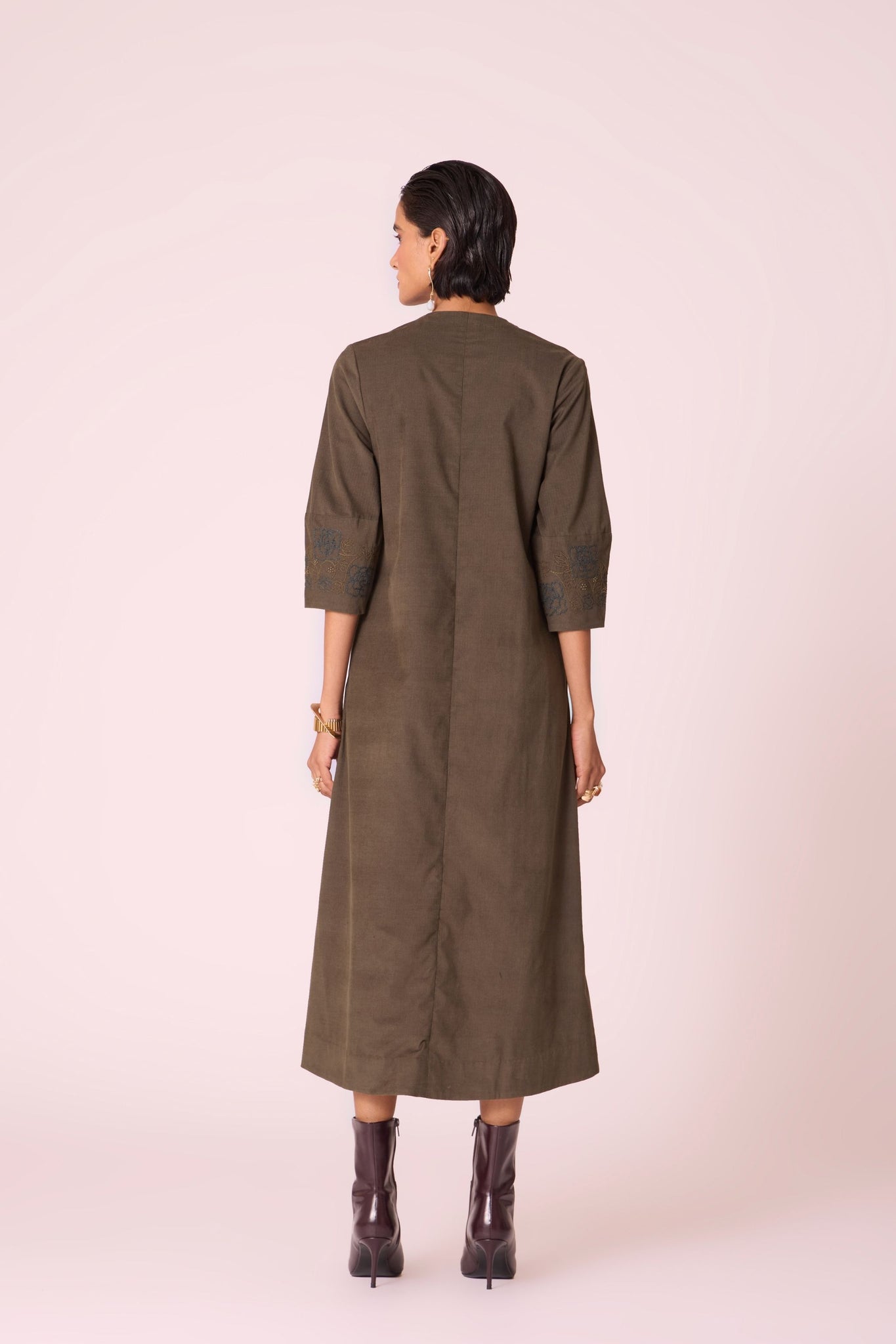 Olive needlecord A-line dress with drop shoulder, hand-embroidered cuff, deep scoop neckline, and in-seam pockets.