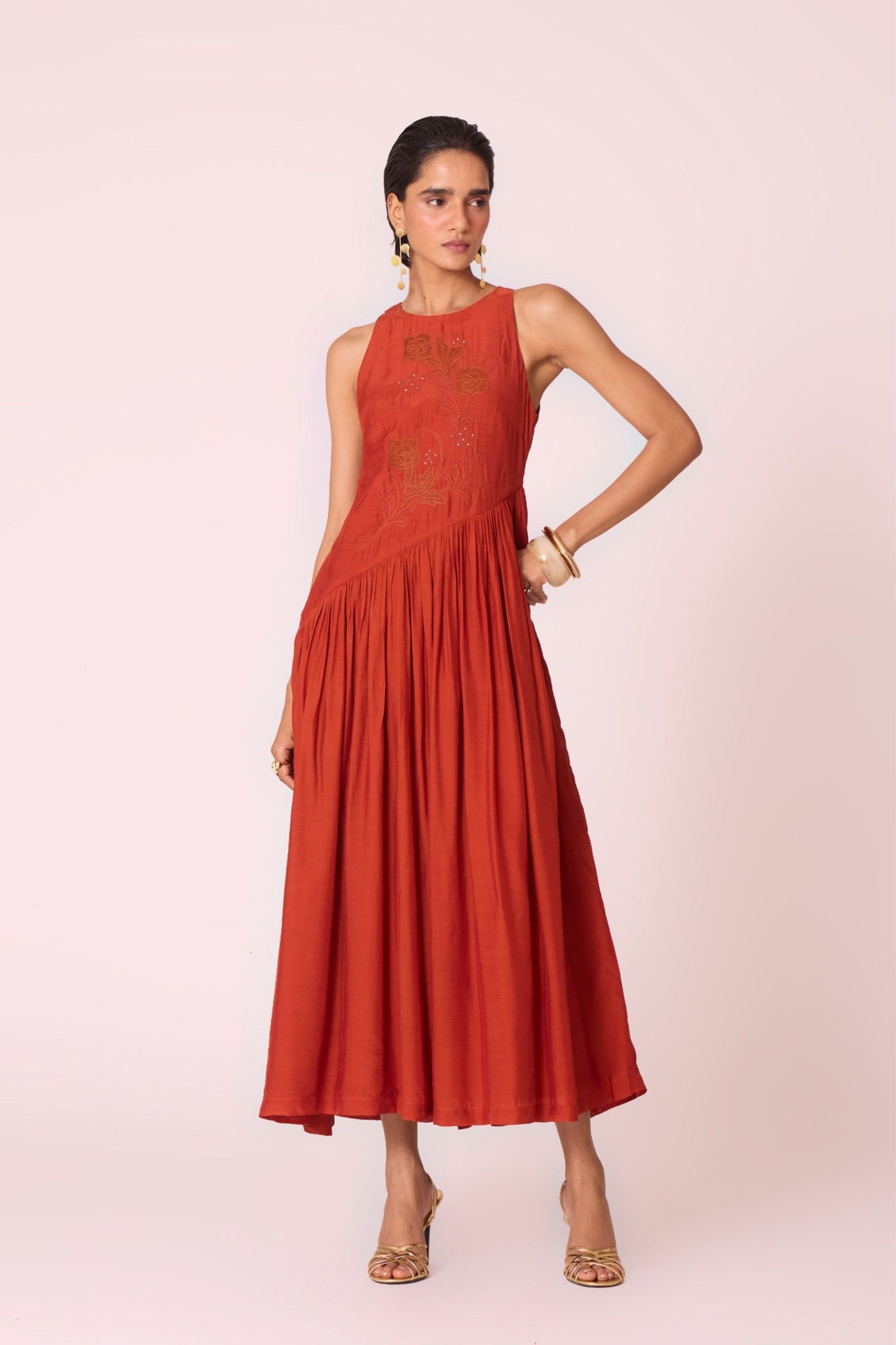 Rust cupro midi dress with hand-embroidered bodice, asymmetric gathered waist, and rouleau back button.
