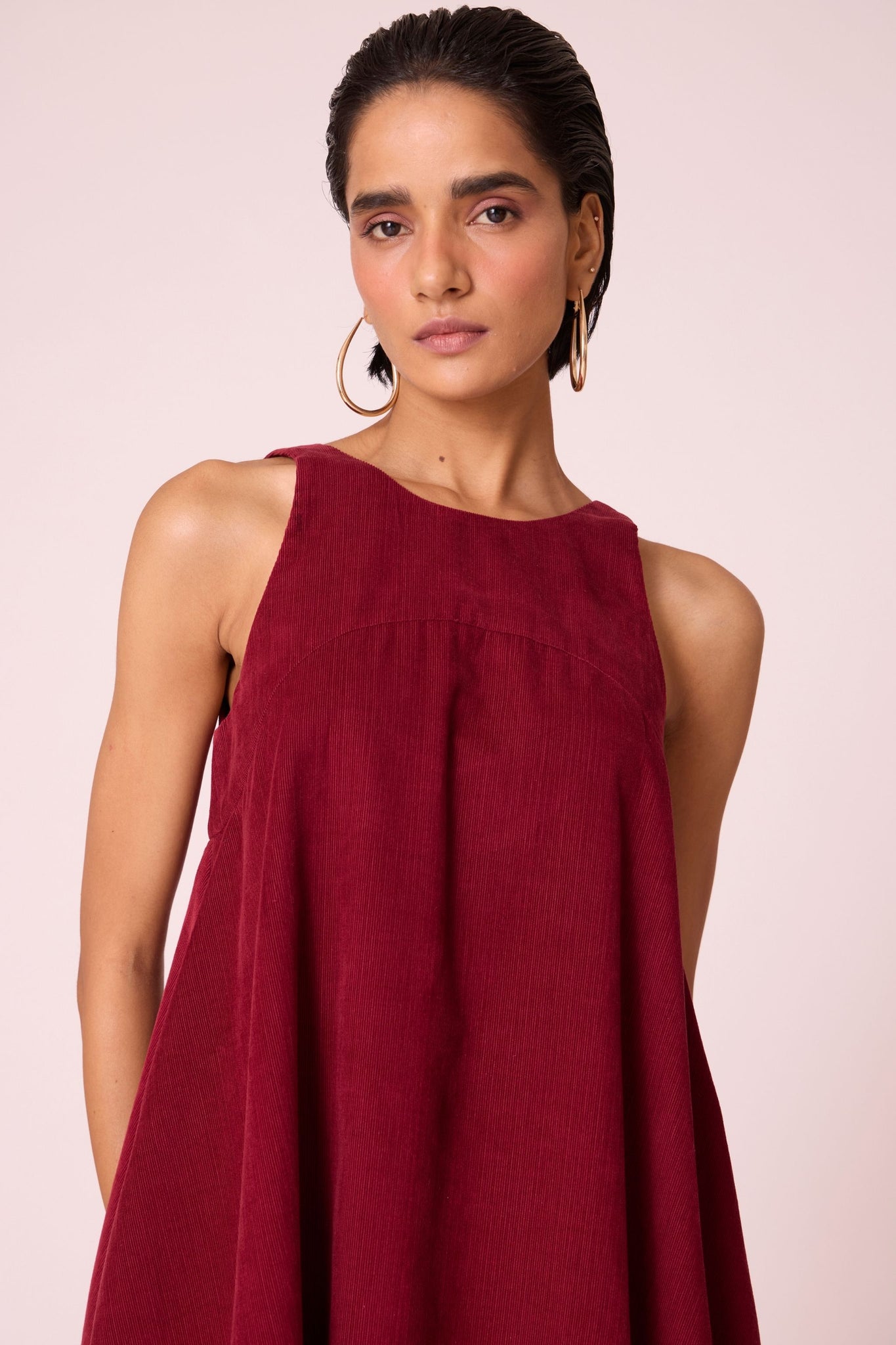 Cherry needlecord tent dress with incut shoulder, low scoop back, and in-seam pockets.
