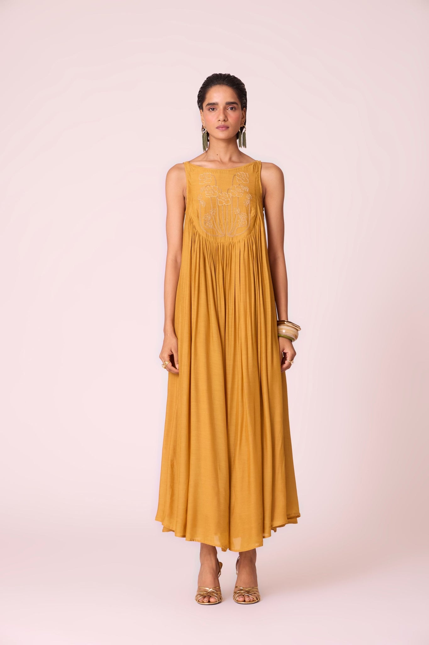 Yellow cupro maxi dress with hand-embroidered yoke, low scoop back with elastic strap, full lining, and light waist gathers.
