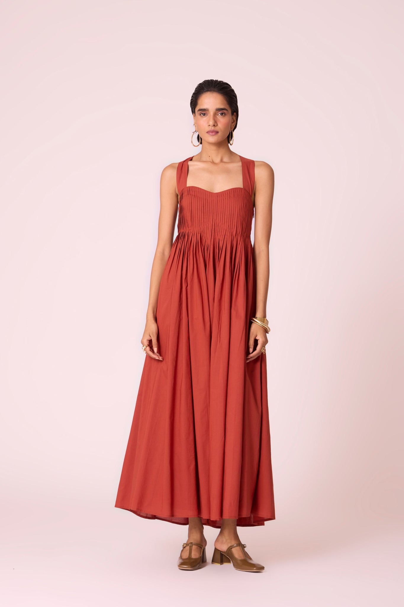 Rust pleated dress in organic cotton voile with a square neckline, thick straps, and a fully lined flared silhouette.
